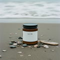 Low Tide sea salt and orange soy candle on a beach with the ocean behind